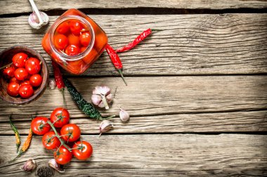 Bir bardak turşu domates sarımsak ve otlar ile jar. Ahşap bir arka plan üzerinde.