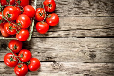 Olgun domates bir sepet içinde. Ahşap bir arka plan üzerinde.