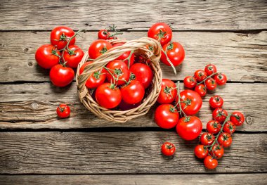 Olgun domates bir sepet içinde. Ahşap bir arka plan üzerinde.