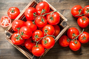 Bir kutu içinde taze domates. Ahşap bir masaya.
