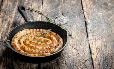 Sosis kekik ile bir tavada kızartma. Ahşap bir arka plan üzerinde.