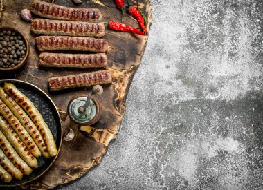 Bir tava içinde baharatlar ile kızarmış sosis. Rustik arka plan üzerinde.