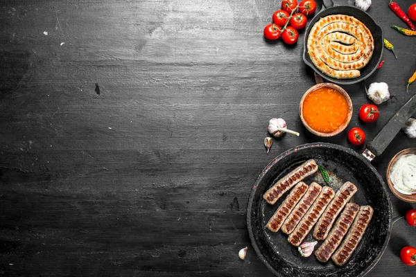 Sarımsak, otlar ve sıcak biber ile kızarmış sosis. Siyah arka plan üzerine.