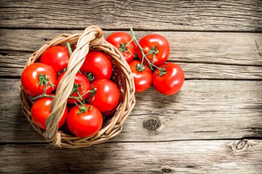 Olgun domates bir sepet içinde. Ahşap bir arka plan üzerinde.