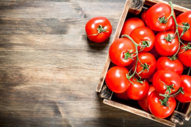 Bir kutu içinde taze domates. Ahşap bir masaya.
