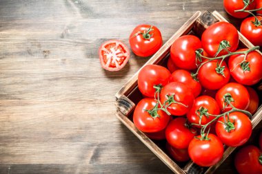 Bir kutu içinde taze domates. Ahşap bir masaya.