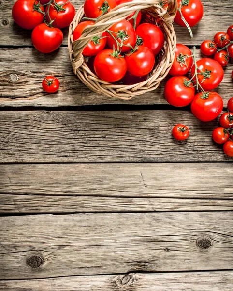 Olgun domates bir sepet içinde. Ahşap bir arka plan üzerinde.