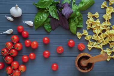 Baharatlı gri arka planda kiraz domatesli Farfalle makarnası.