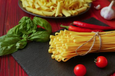 Kırmızı ahşap arka planda makarna tagliatelle ve garganelli