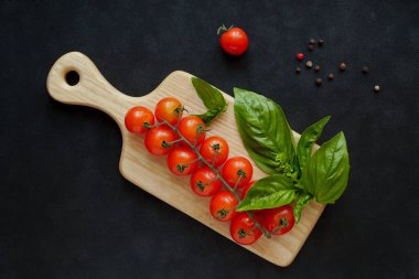 Mutfak tahtasındaki fesleğenli domates dalı.