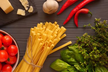 Baharatlı otlar ve sebzelerle çevrili masada Tagliatelle makarnası.