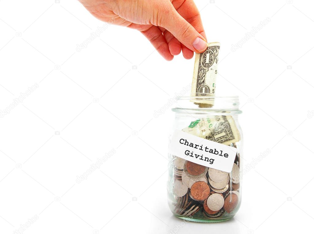 hand putting a dollar into Charitable Giving jar, isolated on white