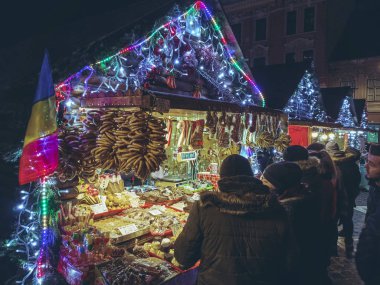 Brasov, Romanya - 2 Aralık 2018: İnsanlar satın geleneksel simit, kurabiye ve renkli ışıklı ve süslü durak gece Belediye Meydanı'nda adil Noel sırasında gösterilen tatlılar.