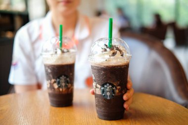 Bangkok, Tayland - 22 Mayıs 2018: El ile krem şanti ve toz kahve kahverengi masa ve Starbucks kahve işareti üzerinde içki 