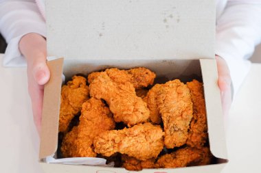 Lezzetli çıtır kızarmış tavuk sopaları ve atıştırmak için kanatları tutan el gıda arka plan veya doku ve ev yapımı kavramı beyaz kutularını hizmet.