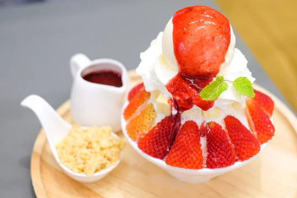 Strawberry kakigori (Japanese shaved ice dessert flavor with vanilla ice-cream) or bingsu (Korea dessert) serve on white bowl with strawberry sauce & peanut for sweet food background or texture.