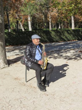 MADRID, SPAIN - CIRCA OCTOBER 2017: unidentified street musician playing alto saxophone at Retiro park in Madrid clipart