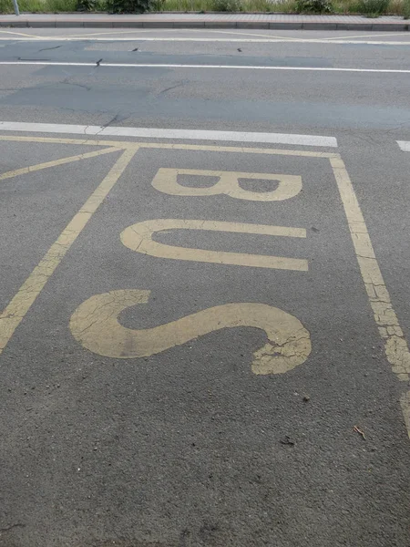yellow bus stop sign painted on the road