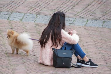 Siena, İtalya - Nisan 2016 yaklaşık: tanımlanamayan kız köpeğiyle oturuyor ve onun smartphone kontrol