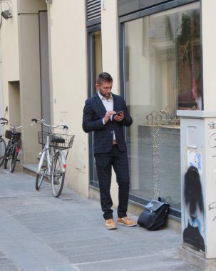 Florence, İtalya - Ekim 2018 yaklaşık: zarif genç adam cep üzerinde arama iş elbiseli