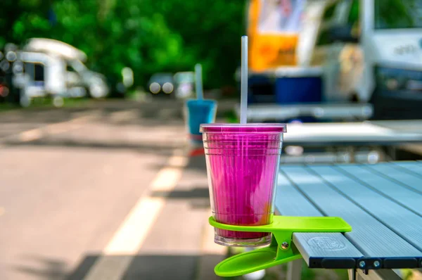 Plastic Cup in clip-on table Cup Holder. Concept of travel accessories for outdoors eating. Desk Clip on Cup Holder.