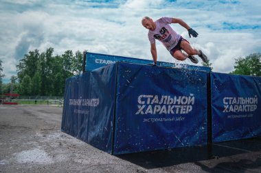 Rusya, Tomsk, 1 Temmuz 2018 - adam su engel parkuru üzerinde üstesinden gelir. Eestrremal spor. 