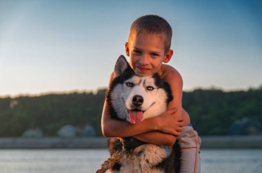 Sevimli çocuk güzel Siberian dış yapraklar sarılma. Çocuk yaz akşam kumsalda huske köpek onun boynuna sarılarak.