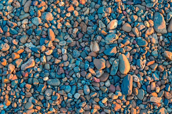 Fundo de cascalho, seixos e pedras à luz do sol à noite . — Fotografia de Stock