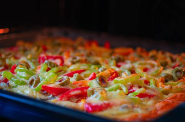 Pizza fırında pişirilir. Et, domates, tatlı biber, peynir ve zeytin pizza. Üst yan görünüm.