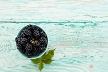 Metin için yer ahşap zemin üzerine kase taze böğürtlen.