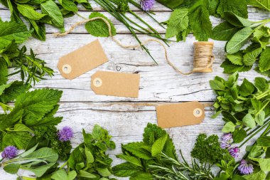 Ahşap bir arka planda taze ve aromatik otlarla çerçevelenmiş..