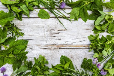 Ahşap bir arka planda taze ve aromatik otlarla çerçevelenmiş..