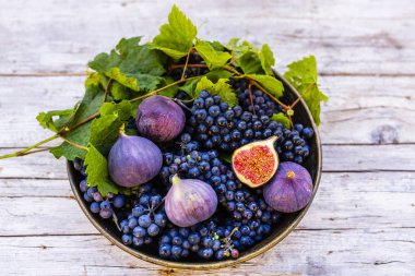 Eski bir tabakta olgun üzüm ve incir.