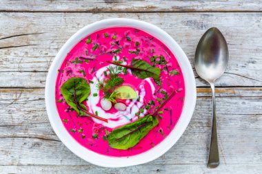 Soğuk pancar çorbası ve taze mevsimlik sebzeler ahşap arka planda. 