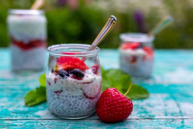 Bahçe masasında yoğurt ve chia ile taze çilekten yapılmış sağlıklı ve lezzetli bir tatlı..