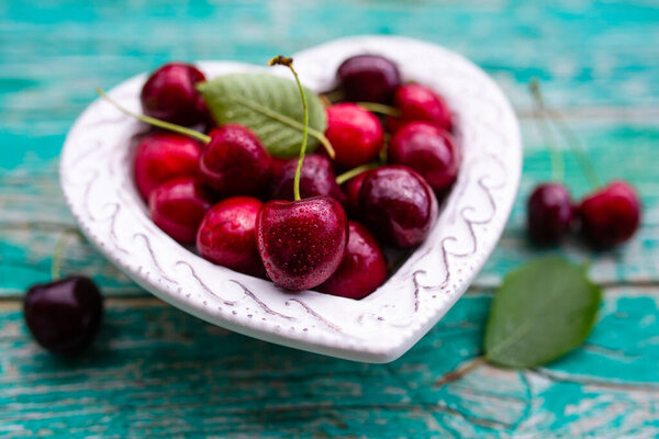 Ripe cherries in a heart-shaped bowl.