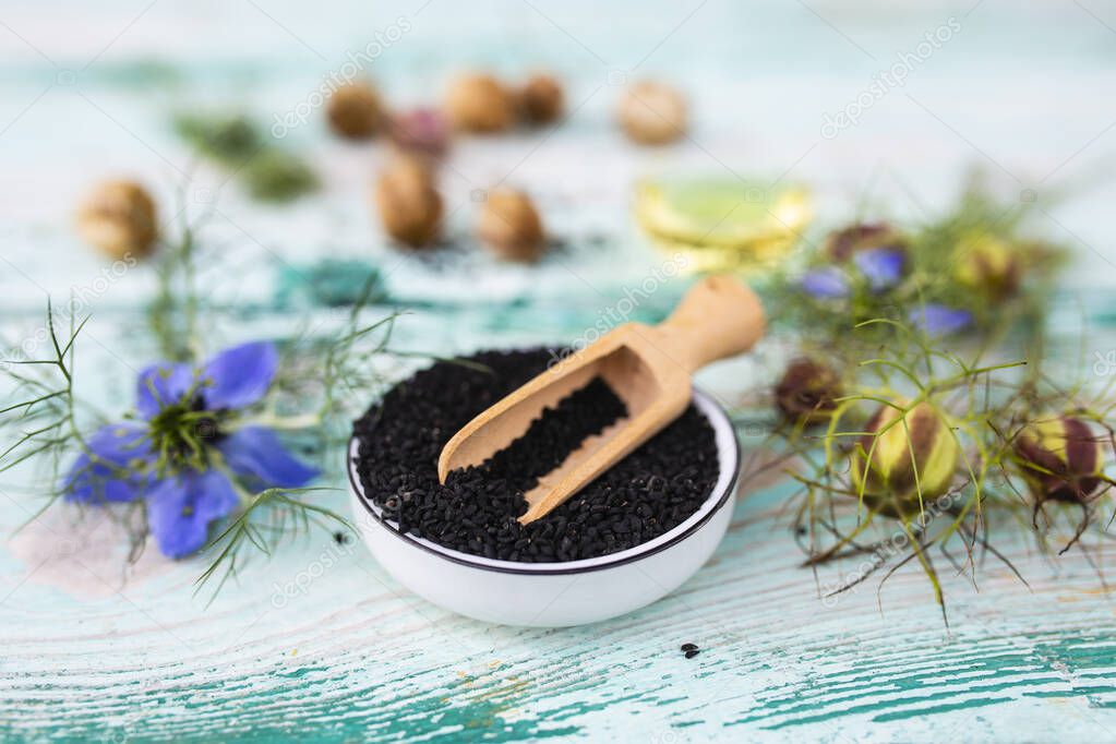 Black cumin flowers and seeds on a wooden background. Healthy diet and alternative medicine.