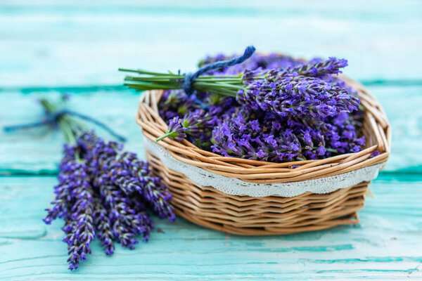 Lavender flowers in a heart-shaped basket on a wooden background.