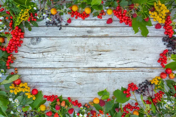 Ahşap arka planda sonbahar yaprakları ve meyveler. Metin için alanı olan çerçeve.