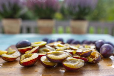 Bahçe masasında olgun erik yarımları.
