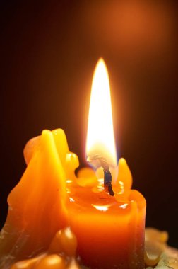 Karanlık odada yanan sarı mum.