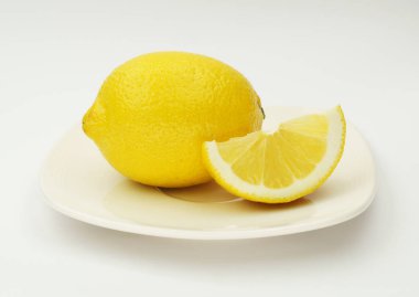 Beyaz bir arka plan üzerinde bir cam daire bir dilim limon ve bir yarım kesilmiş limon var