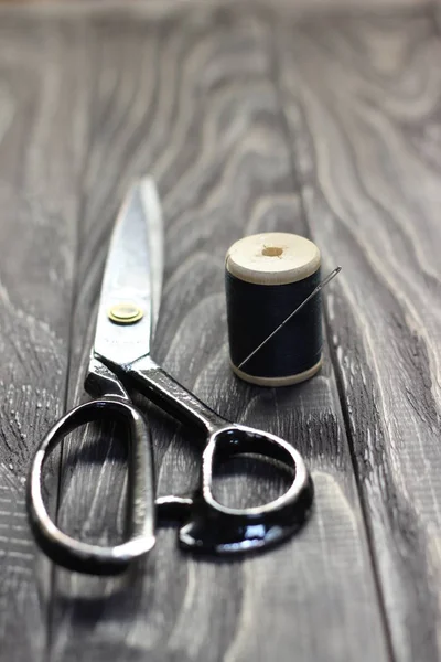 On a black wooden stench, close-up, scissors spool of thread wit — Stock Photo, Image