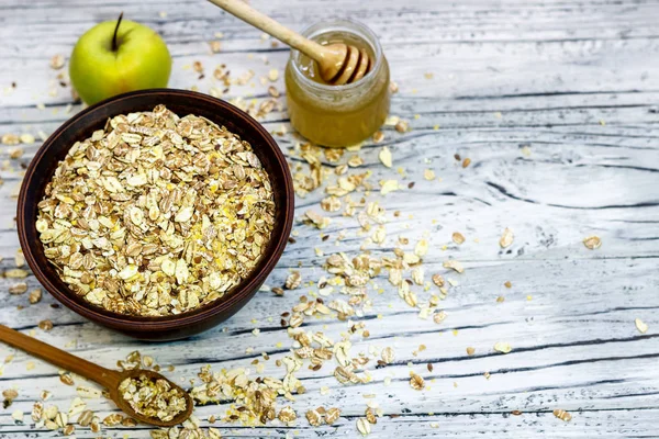 Plate with muesli on a wooden background near apples and honey. — Stock Photo, Image