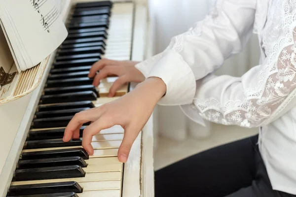 Девушка играет на белом пианино. Руки девушки, нажимающей клавиши пианино — стоковое фото