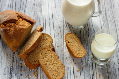 M bir bardak yanında ahşap bir arka plan üzerinde çavdar ekmeği bir dilim