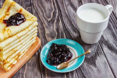 Bal ve bir fincan süt ile beyaz bir tabak üzerinde krep. Lezzetli br