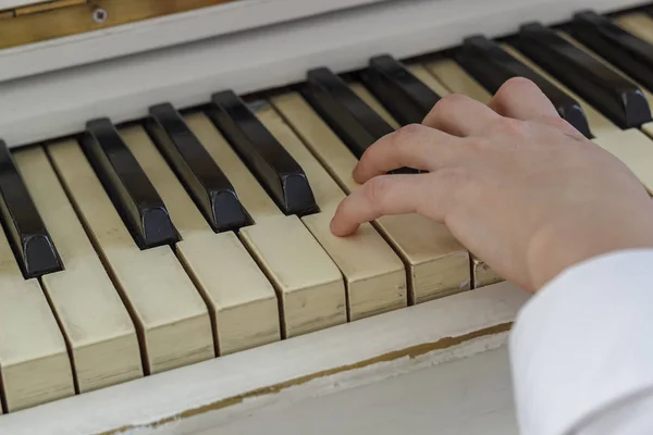 Mani di una giovane ragazza che suona su un pianoforte bianco, primo piano . — Foto Stock