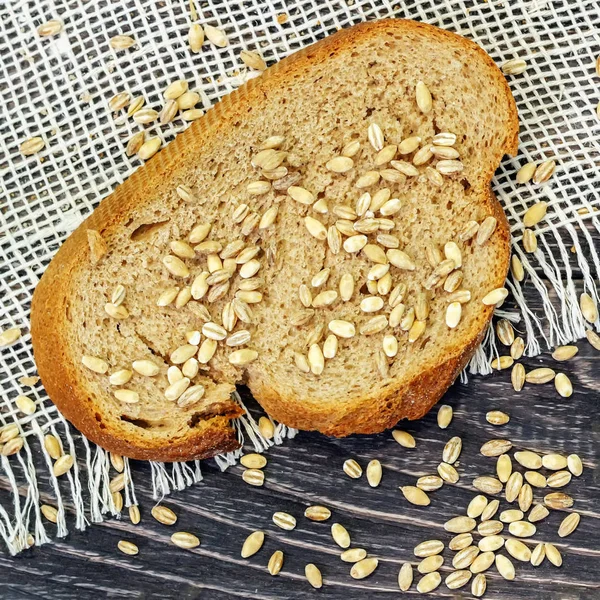 Slices of whole-wheat bread with wheat seeds on a wooden backgro