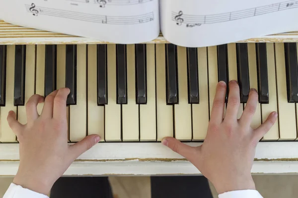 Hands of a young girl playing on a white piano, close-up. — Stock Photo, Image